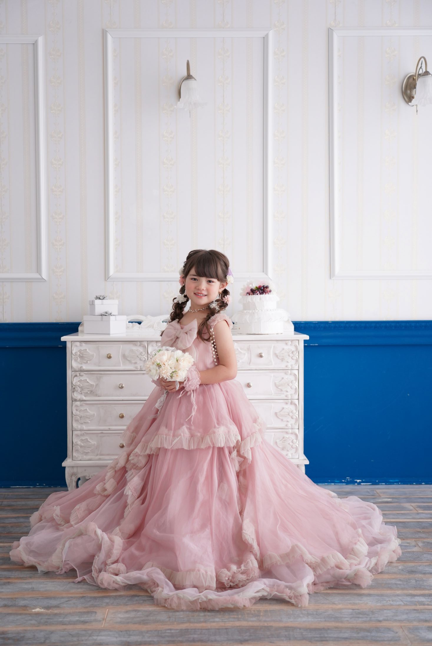 七五三の記念日を迎えた７歳の女の子。オシャレなハウススタジオでドレスを着て笑顔で撮影している写真。テラスモールまつどでの七五三のスタジオ撮影。店舗住所：千葉県松戸市八ヶ崎二丁目8-1 テラスモール松戸3F