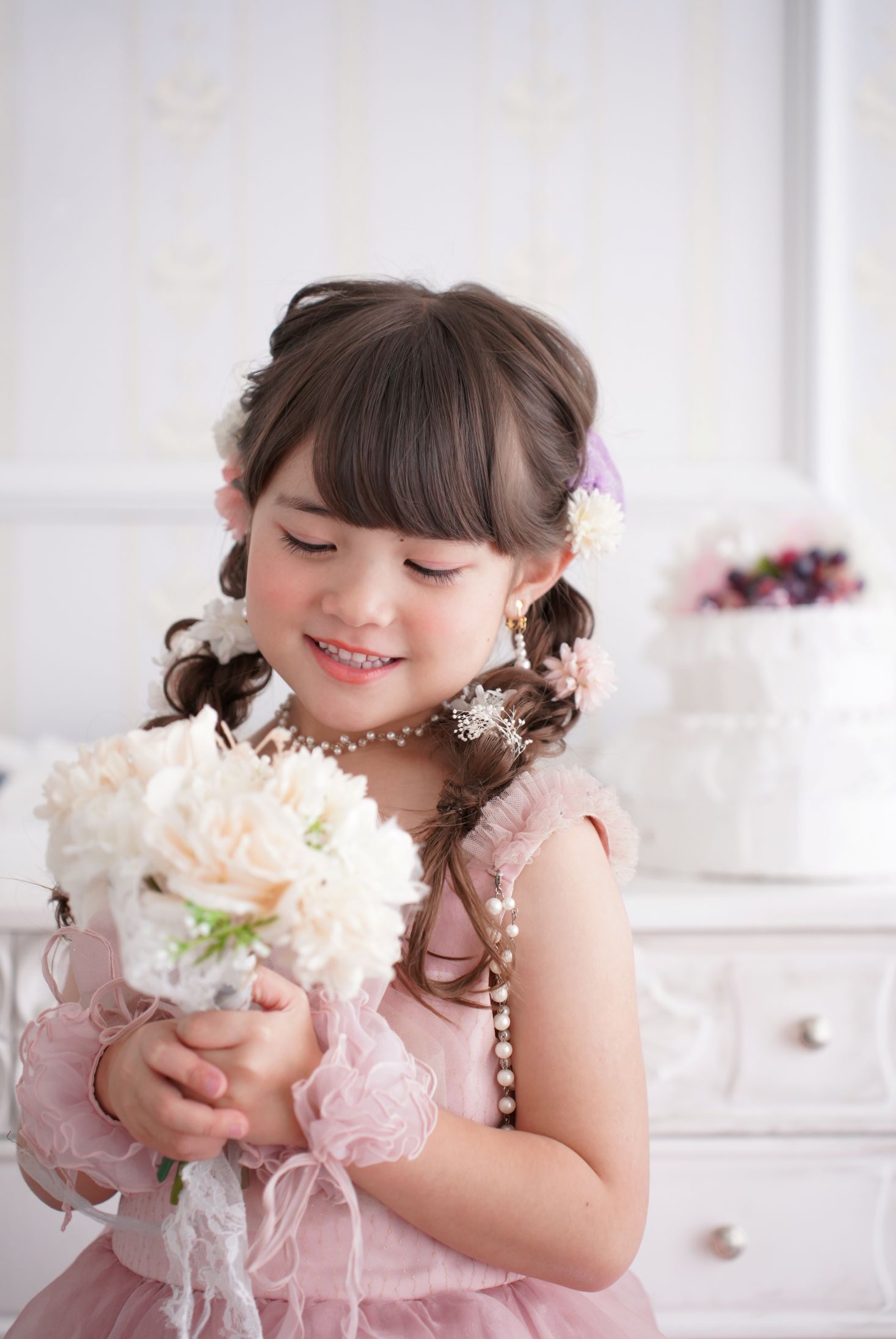七五三の記念日を迎えた７歳の女の子。オシャレなハウススタジオでドレスを着て笑顔で撮影している写真。テラスモールまつどでの七五三のスタジオ撮影。店舗住所：千葉県松戸市八ヶ崎二丁目8-1 テラスモール松戸3F