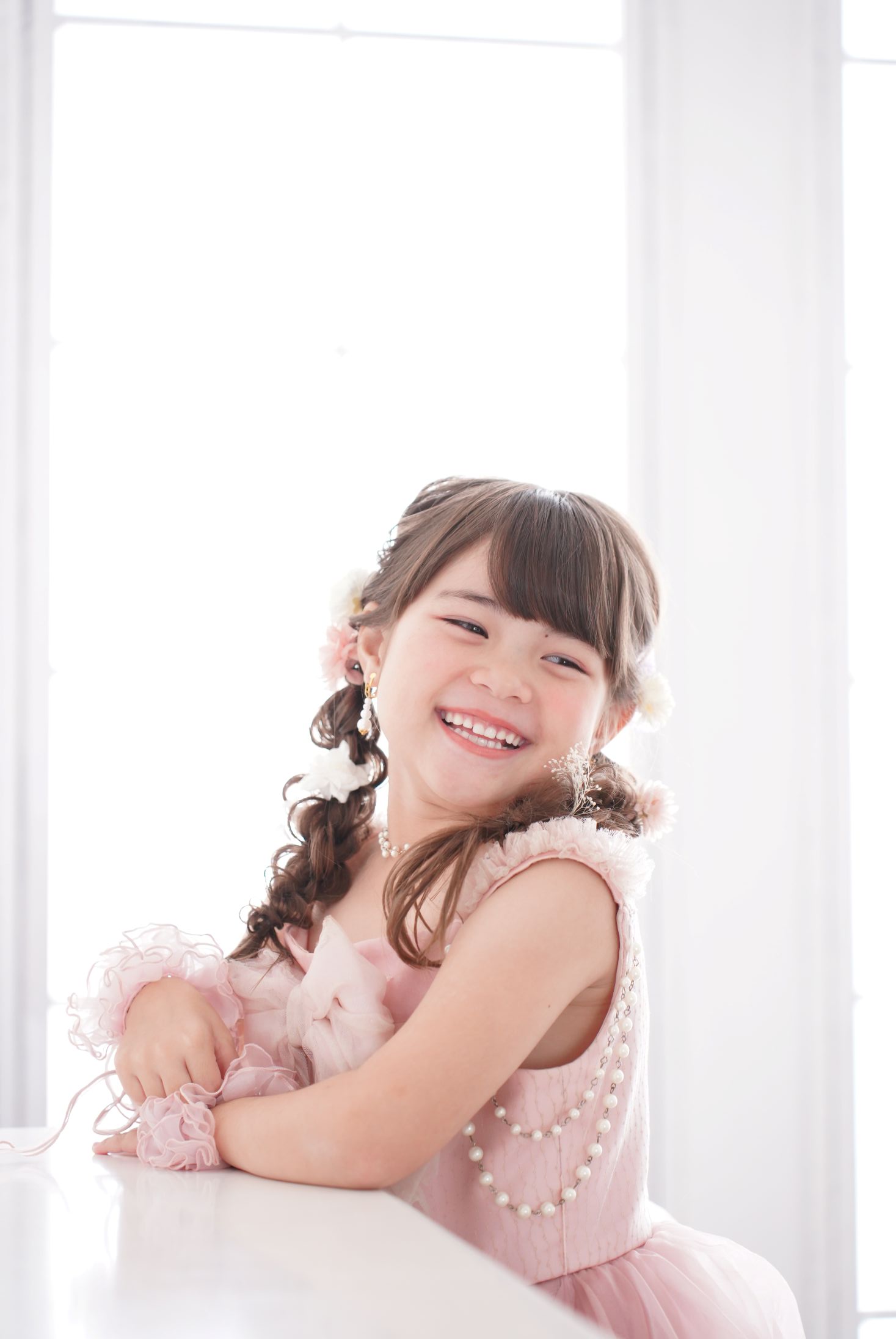 七五三の記念日を迎えた７歳の女の子。オシャレなハウススタジオでドレスを着て笑顔で撮影している写真。テラスモールまつどでの七五三のスタジオ撮影。店舗住所：千葉県松戸市八ヶ崎二丁目8-1 テラスモール松戸3F