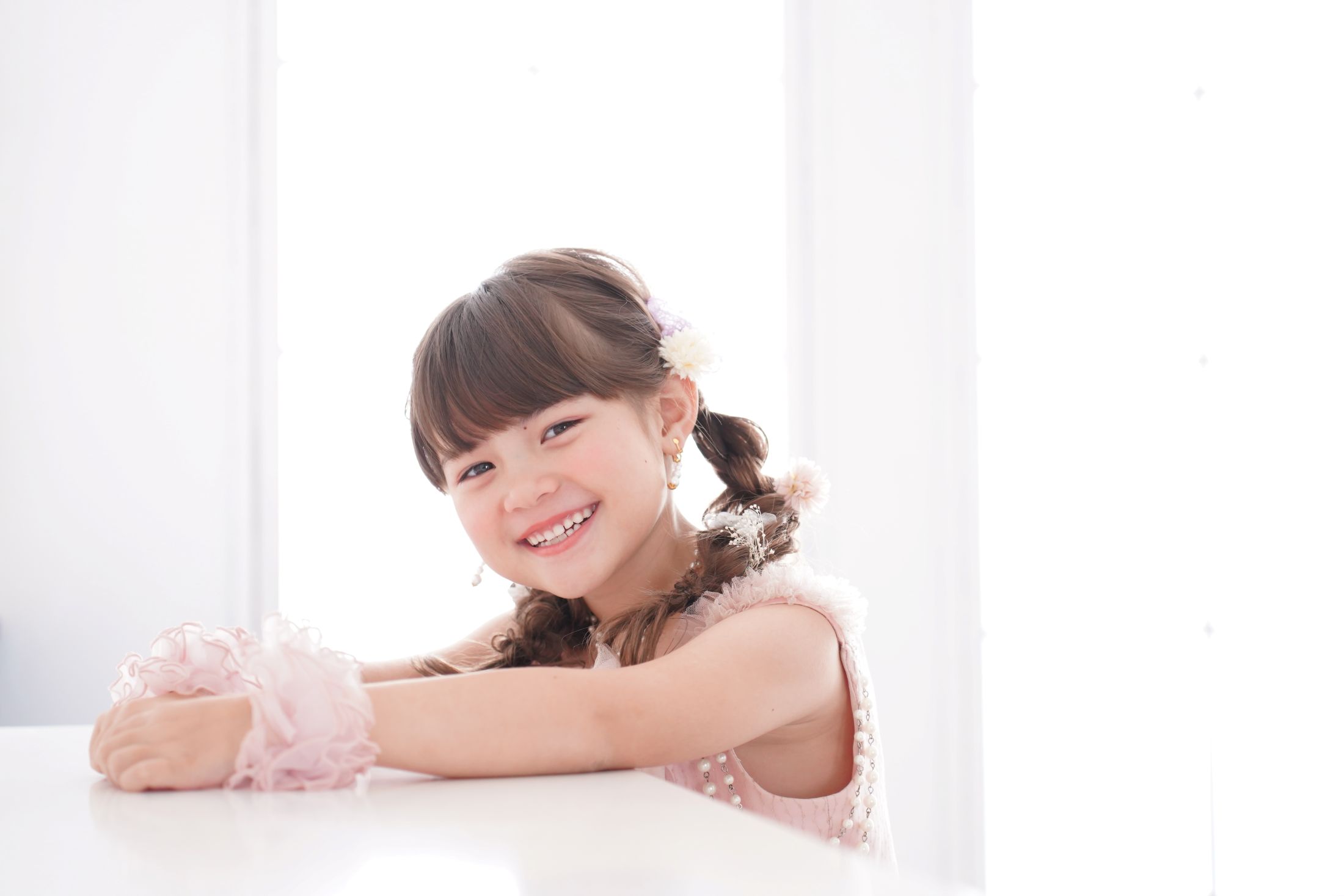 七五三の記念日を迎えた７歳の女の子。オシャレなハウススタジオでドレスを着て笑顔で撮影している写真。テラスモールまつどでの七五三のスタジオ撮影。店舗住所：千葉県松戸市八ヶ崎二丁目8-1 テラスモール松戸3F
