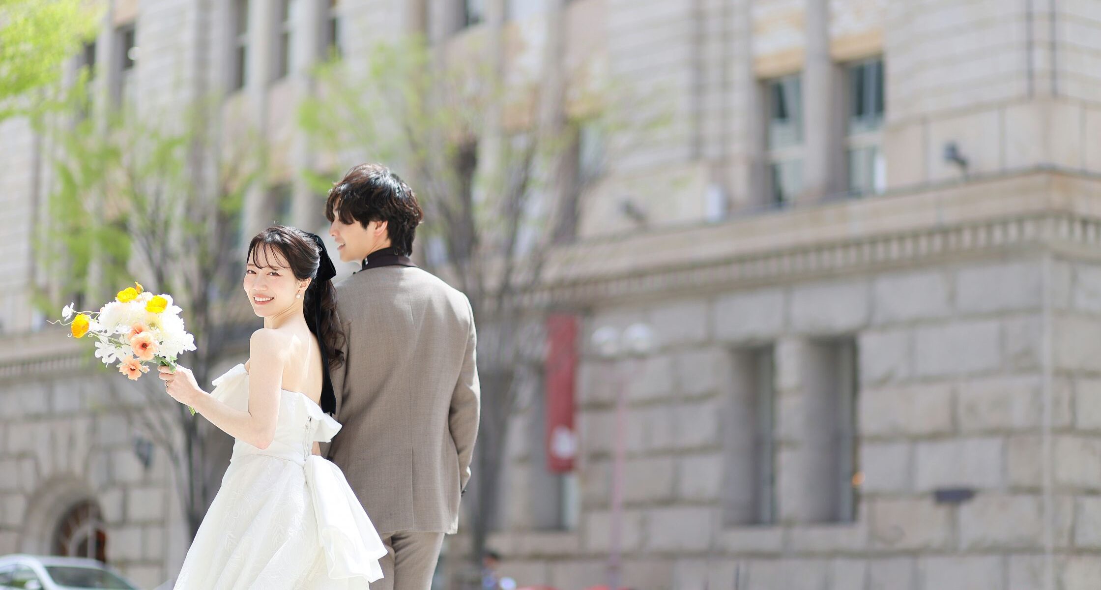 ロケーション撮影をするウェディングドレスの新婦とタキシードの新郎