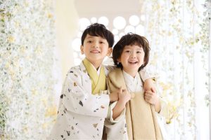 七五三の着物の必需品や選び方は? nicoriオリジナルのテラゾ柄やストライプ柄の羽織袴を着て、明るい笑顔で寄り添う二人の男の子の七五三スタジオ写真