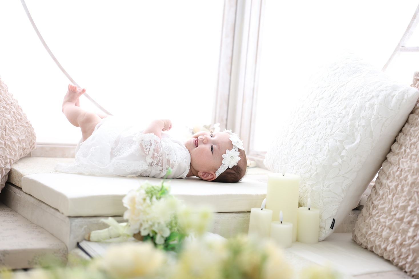 お宮参りで白いドレス風の洋装を着た赤ちゃんのソロ写真。自然光が優しく差し込む一枚。