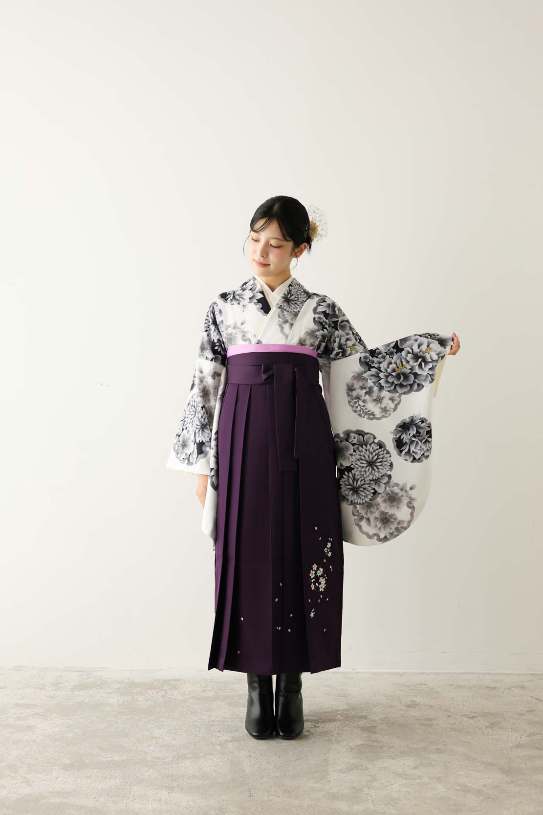 白地に黒・グレーの大きな花柄をあしらった着物に、深い紫の袴を合わせたモダンな卒業袴コーディネート。大学・専門学校の卒業式や謝恩会におすすめの袴レンタルをFURISODE ARCでご用意しています。