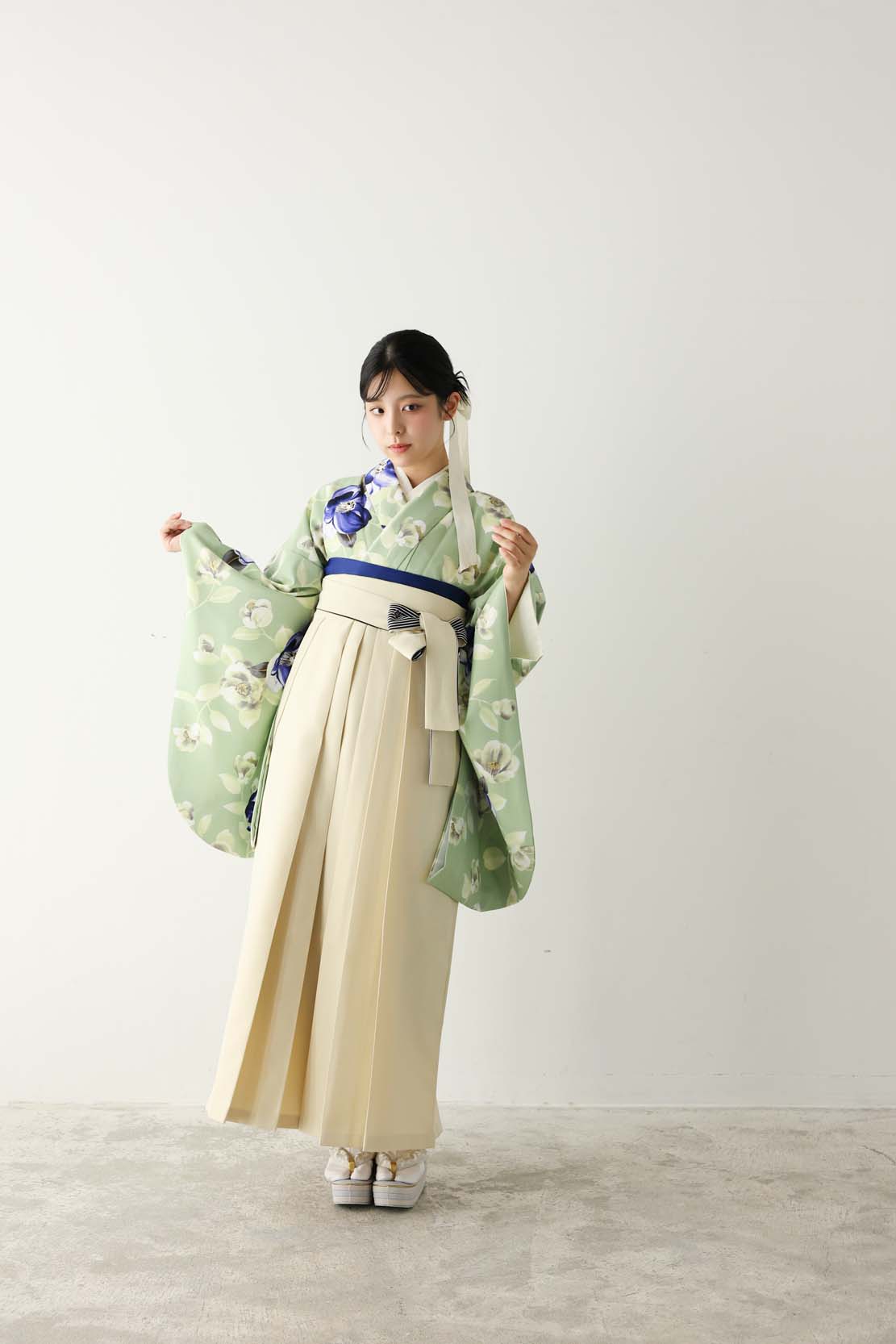淡いグリーン地に青や白の花柄をあしらった着物に、アイボリーの袴を合わせた爽やかなコーディネート。