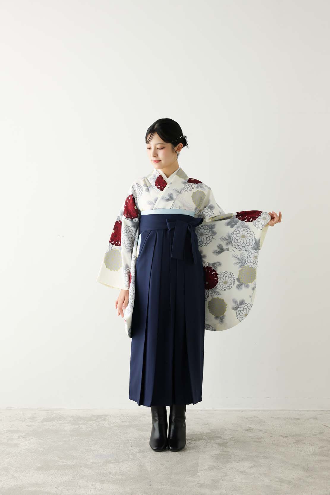 白地に赤やグレーの花柄をあしらった着物に、深い紺色の袴を合わせた上品なコーディネート。