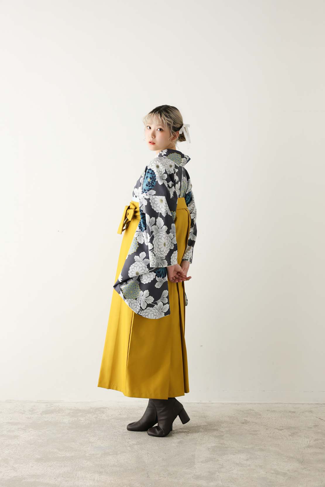 黒地に白や青の菊柄をあしらった着物に、からし色の袴を合わせた印象的なコーディネート。