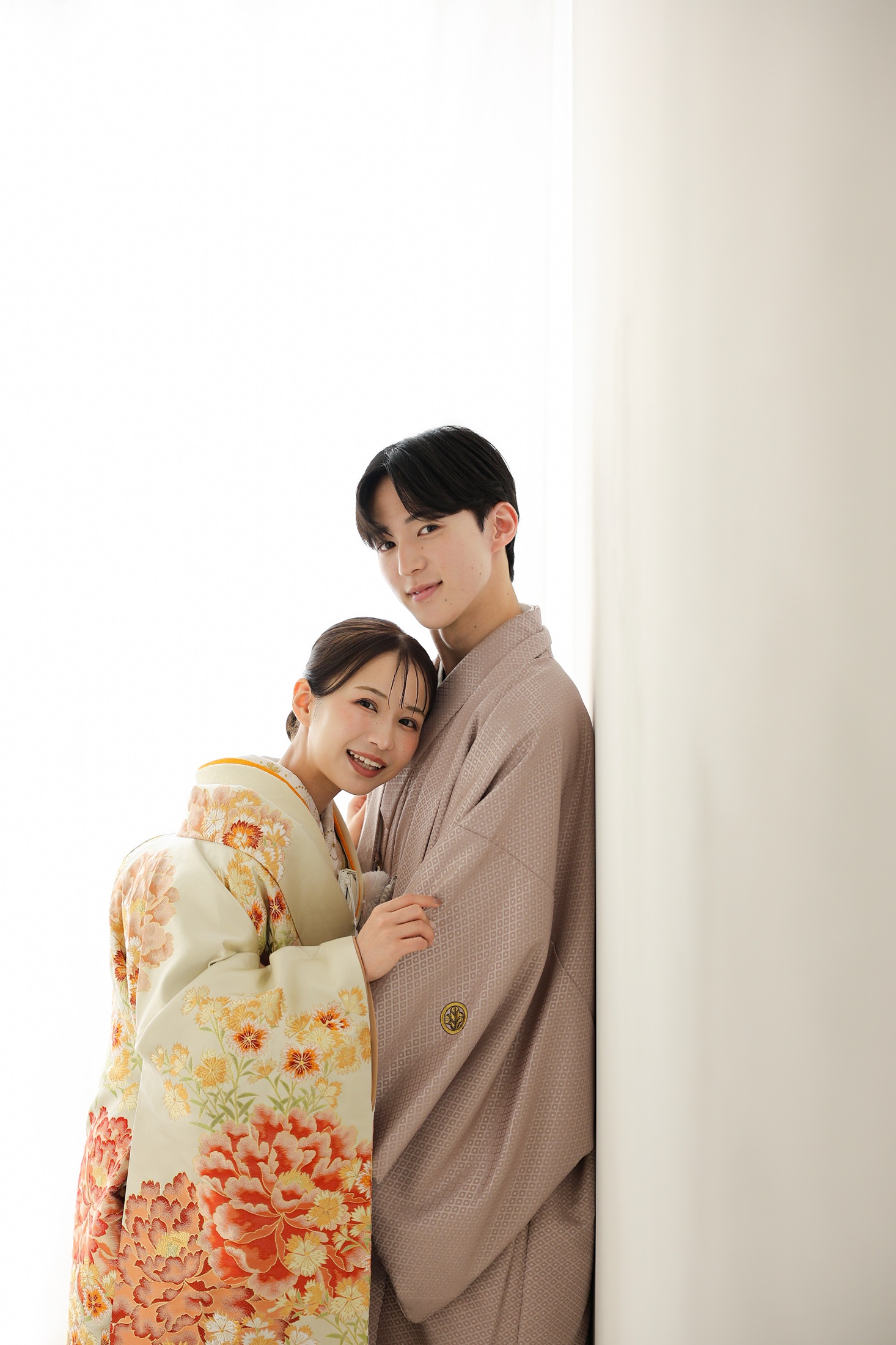 色打掛と袴でフォトウェディングの撮影をする新郎新婦様。真っ白で柔らかな光に包まれる中、オレンジ色が映える色打掛の新婦様と新郎様を撮影している写真。撮影店舗：しんかな大阪南店 住所：大阪府堺市北区長曽根町3069-7