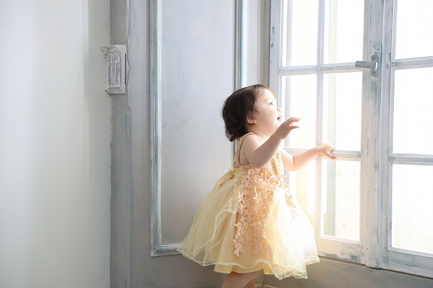 黄色のドレスを着た1歳の女の子の誕生日記念写真。