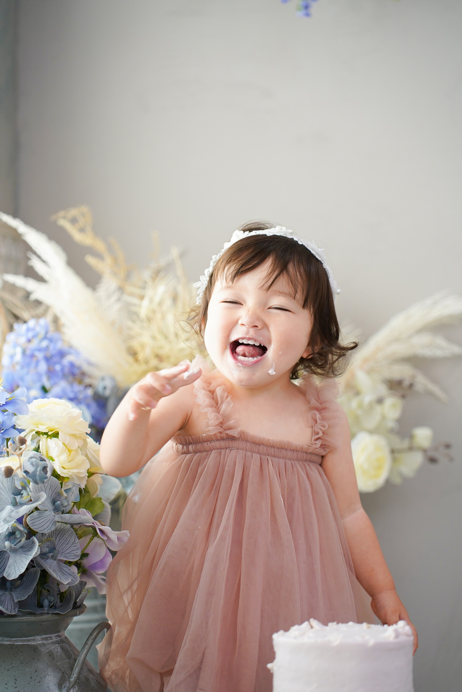 1歳のお誕生日をスマッシュケーキでお祝いする、笑顔あふれる記念写真。特別なバースデーフォトです。