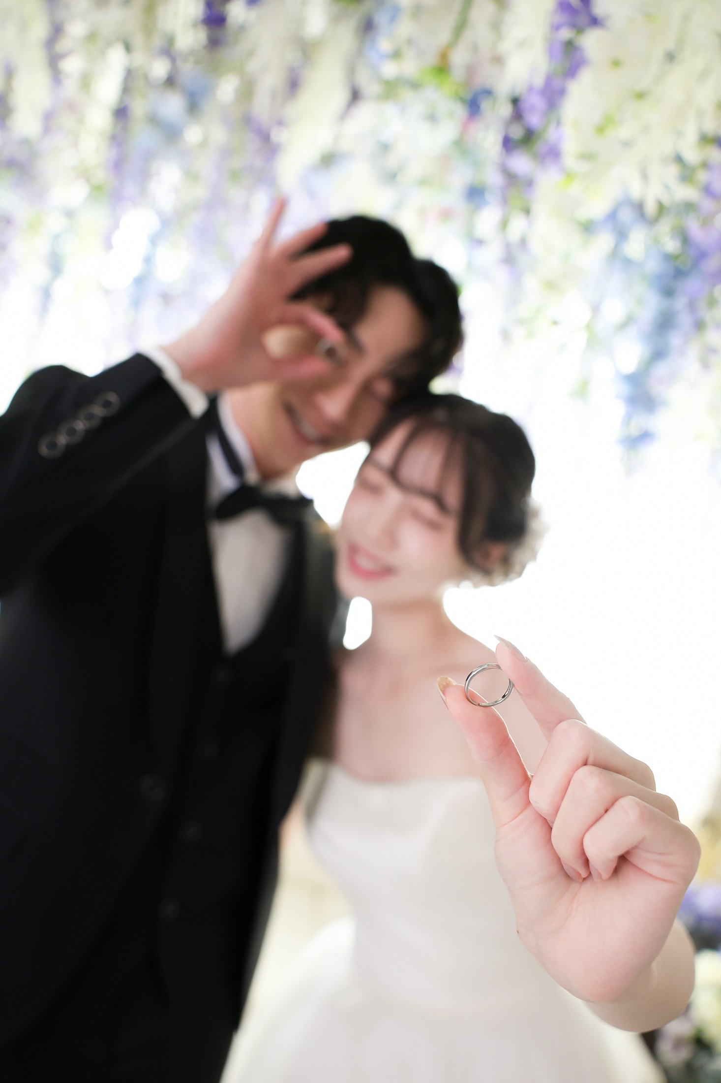 ウェディングドレスとタキシードでフォトウェディングの撮影をする新郎新婦様。新郎新婦様が持つ指輪にフォーカスした写真。撮影店舗:芝ParksideSTUDIO店 住所:東京都港区芝2-1-28 芝アネックスビル1階