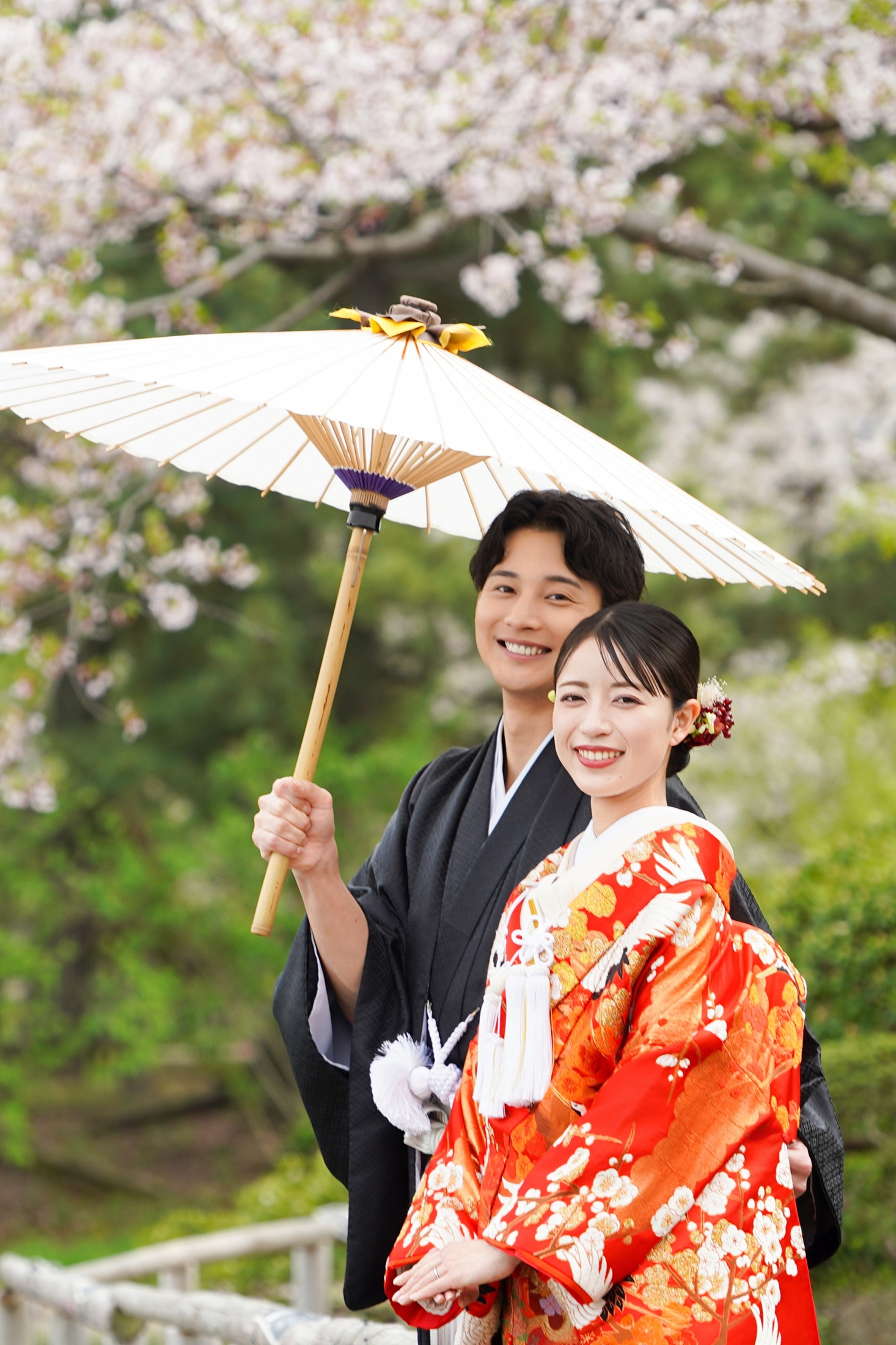 三渓園の日本庭園で和装を着て結婚式の前撮りをする新郎様と新婦様。和傘と赤の色打掛が王道の美しさで庭園の雰囲気ともマッチしている 。撮影：STUDIOARC