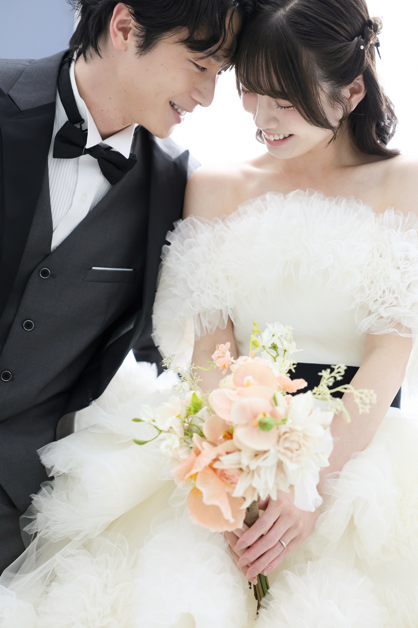 ェディングドレスとタキシードでフォトウェディングの撮影をする新郎新婦様。ナチュラルカラーのブーケを抱える新婦様と新郎様が笑顔で顔を寄せ合う様子を撮影している写真。 撮影店舗:ららテラスHARUMI FLAG店 住所:東京都中央区晴海五丁目2番31号 ららテラス HARUMI FLAG 3階