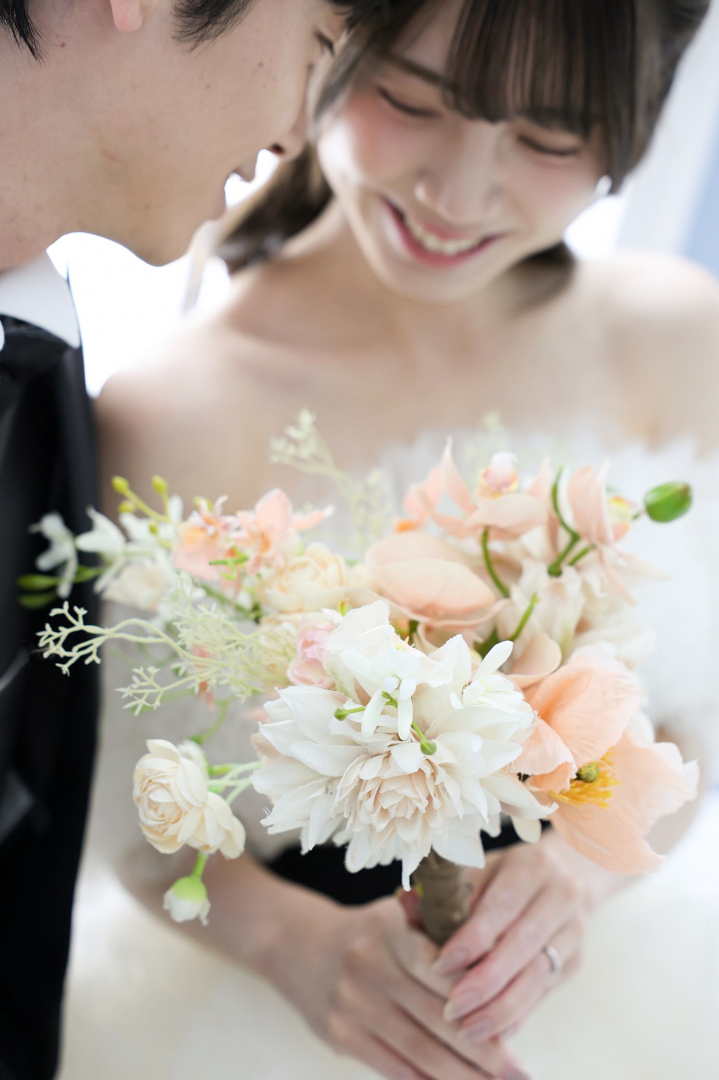 ウェディングドレスとタキシードでフォトウェディングの撮影をする新郎新婦様。ナチュラルカラーのブーケを抱える新婦様の手元にフォーカスしている写真。 撮影店舗:ららテラスHARUMI FLAG店 住所:東京都中央区晴海五丁目2番31号 ららテラス HARUMI FLAG 3階