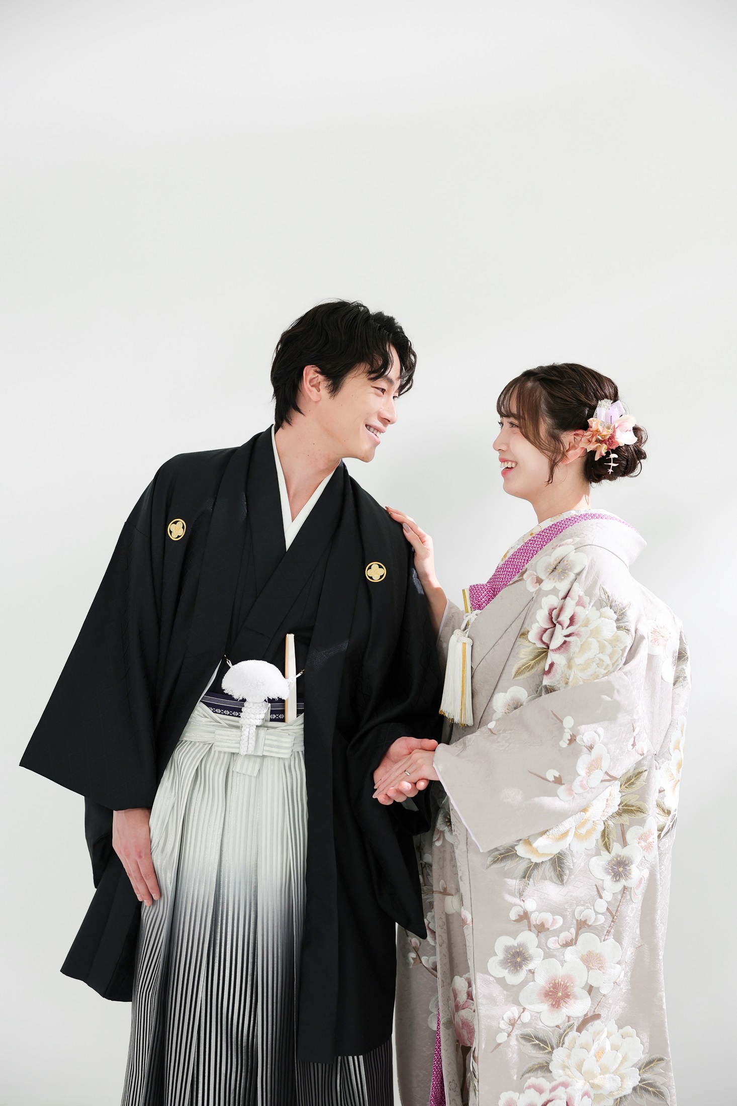 色打掛と袴でフォトウェディングの撮影をする新郎新婦様。真っ白の壁を背景に、淡い色合いの色打掛が映える新婦様と新郎様を撮影している写真。撮影店舗:ららテラスHARUMI FLAG店 住所:東京都中央区晴海五丁目2番31号 ららテラス HARUMI FLAG 3階