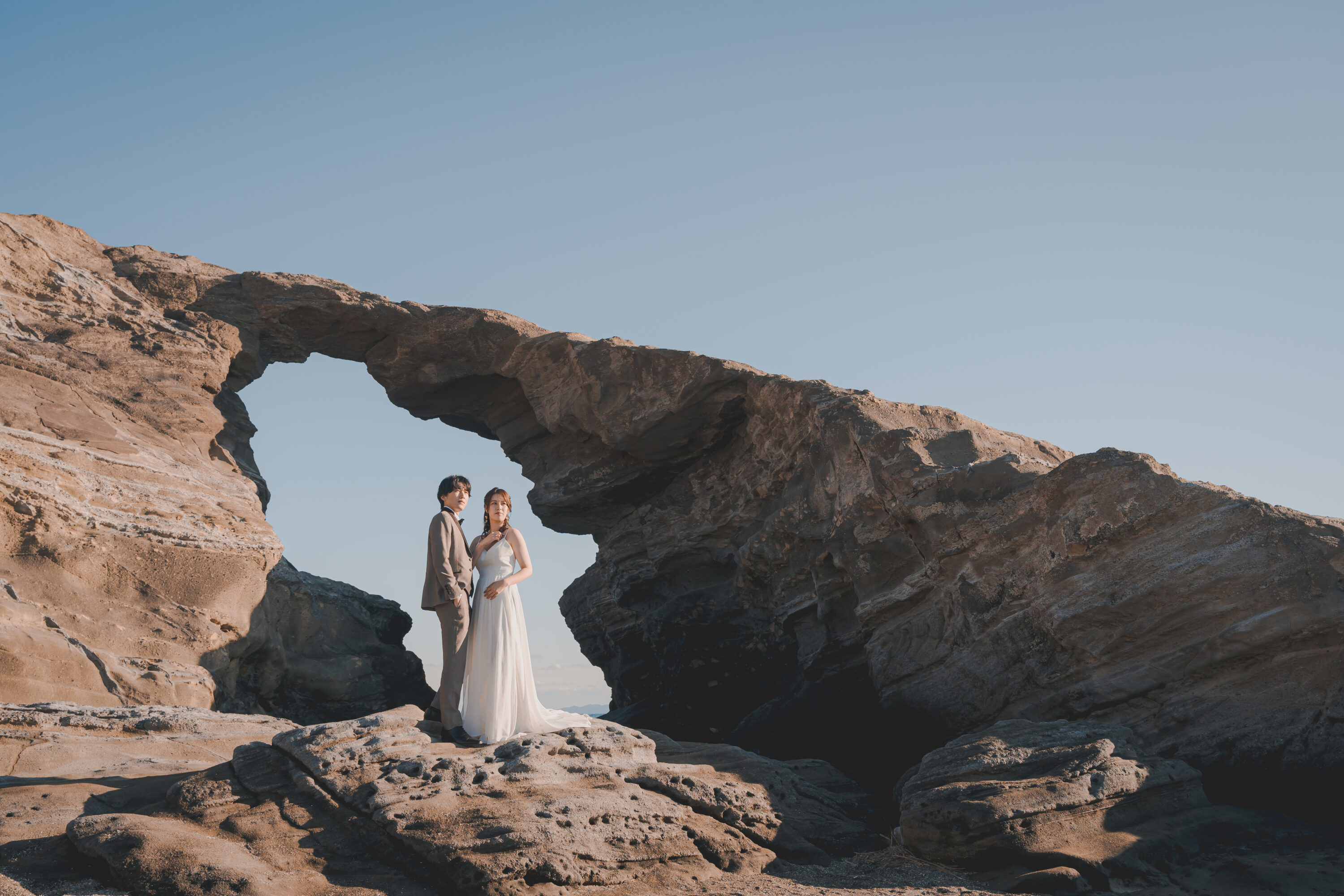 城ケ島でフォトウェディングの撮影をしている新郎新婦様の写真。白のウェディングドレスとタキシードが青空に映える人気のロケーション地。撮影：STUDIOARC