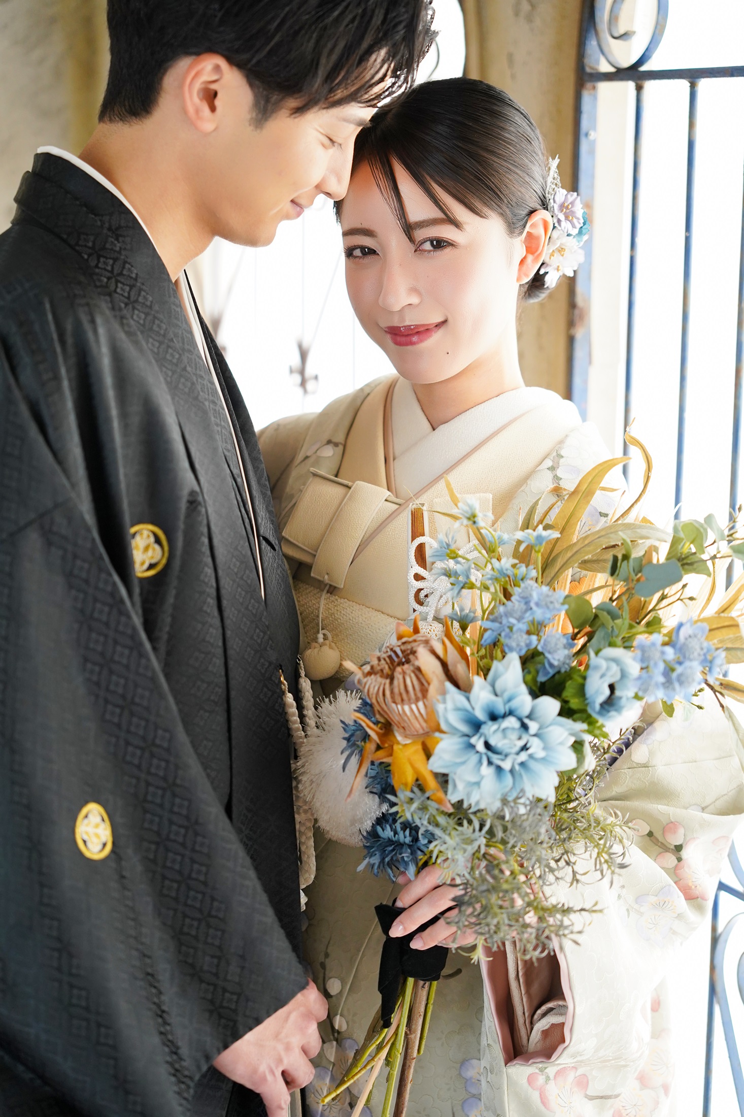 結婚式の前撮り撮影をする紋付き袴を着た新郎様と色打掛を着た新婦様。アンティーク家具の背景の中で撮影している写真。 撮影店舗：STUDIOARC横浜店 住所：神奈川県横浜市中区山下町84-5 メトロタワー山下町 4F