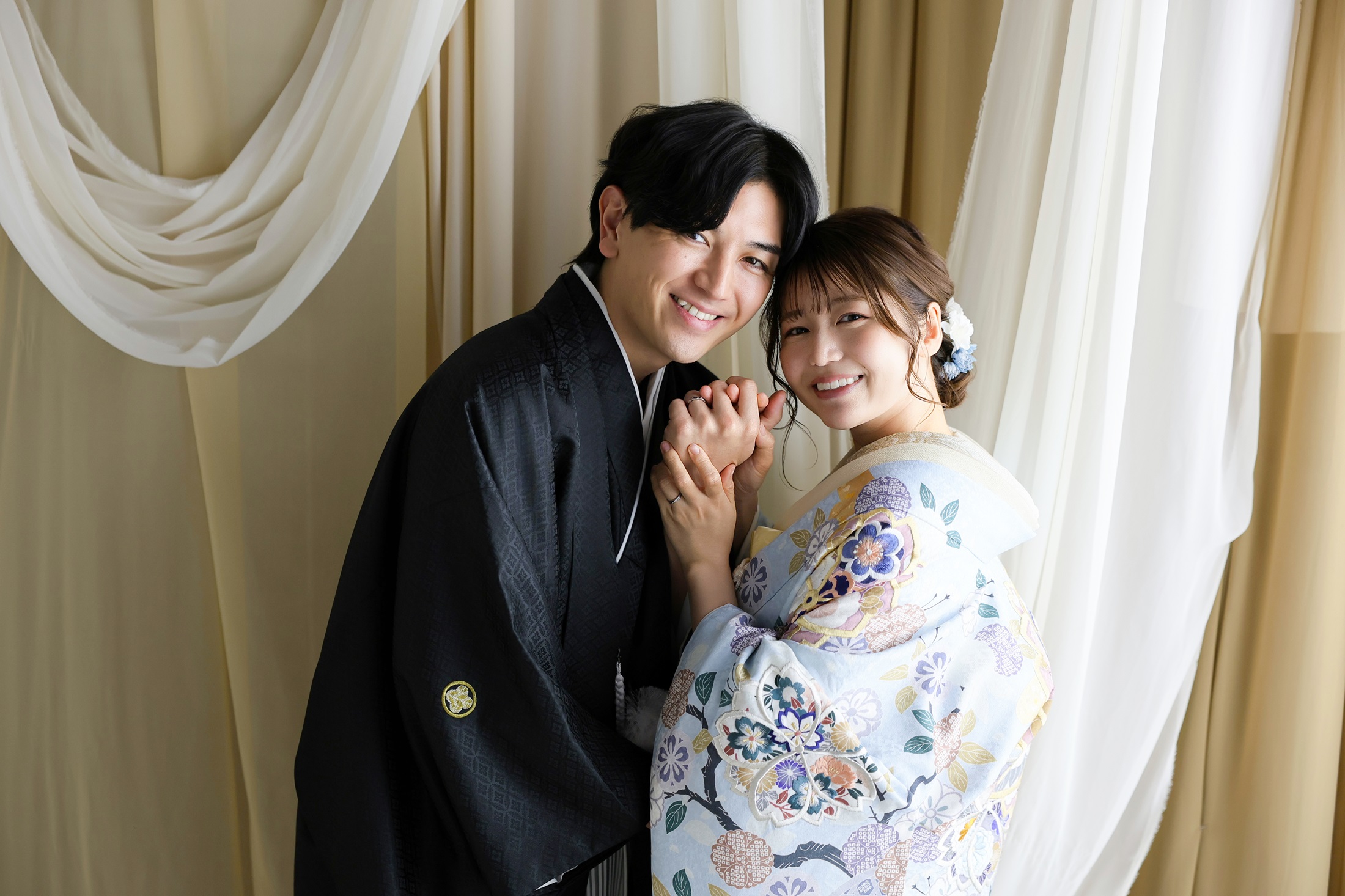 色打掛と袴でフォトウェディングの撮影をする新郎新婦様。ナチュラルで柔らかなカーテンを背景に、水色の色打掛が映える新婦様と新郎様を撮影した写真。撮影店舗：神戸ハーバーランド店 住所：兵庫県神戸市中央区東川崎町1-5-5 ハーバーランド煉瓦倉庫