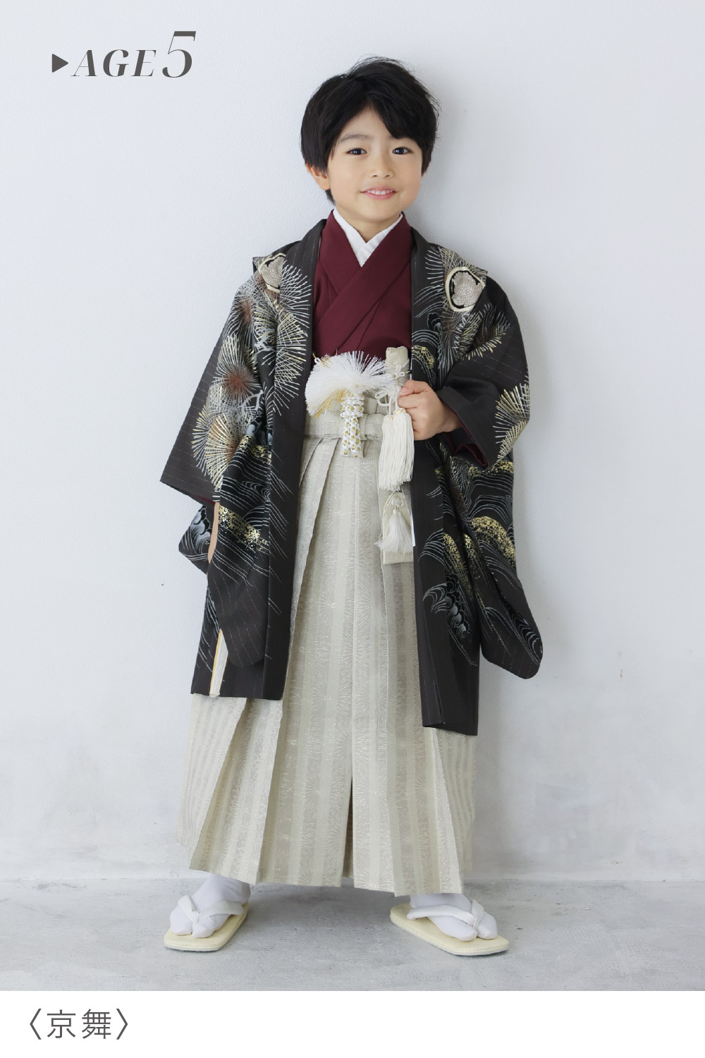 「京舞」の5歳男の子用衣装を着用し、黒地に金の波松柄羽織と白の縞袴、扇子でおしゃれにコーディネートした七五三着物スタイル
