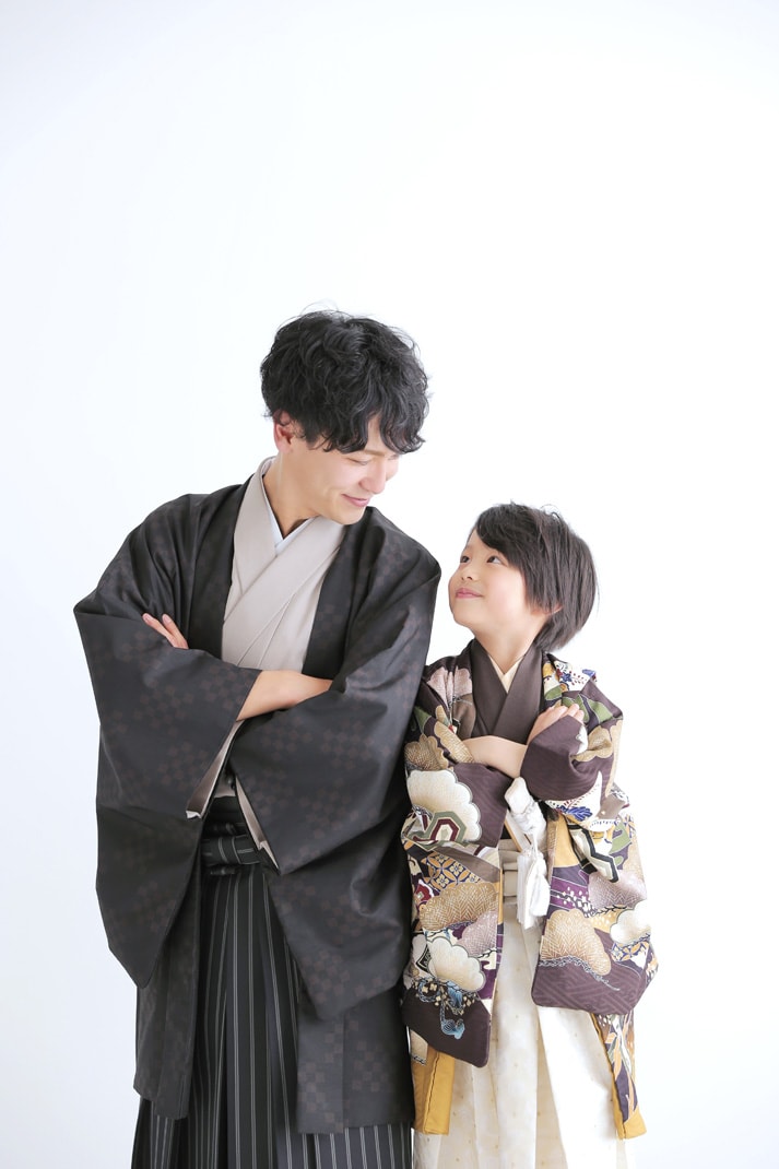 着物姿の父親と息子が腕を組んで見つめ合い微笑む七五三の写真
