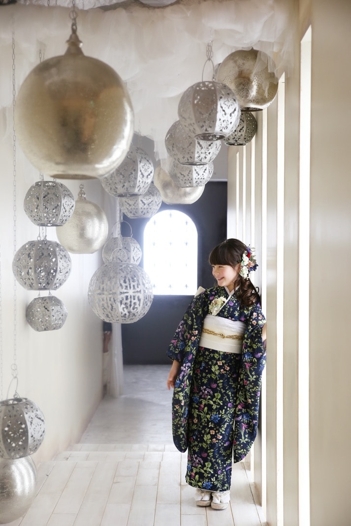 たくさんの丸いランプシェードが飾られた通路でボタニカル柄の着物を着て佇む女の子の写真
