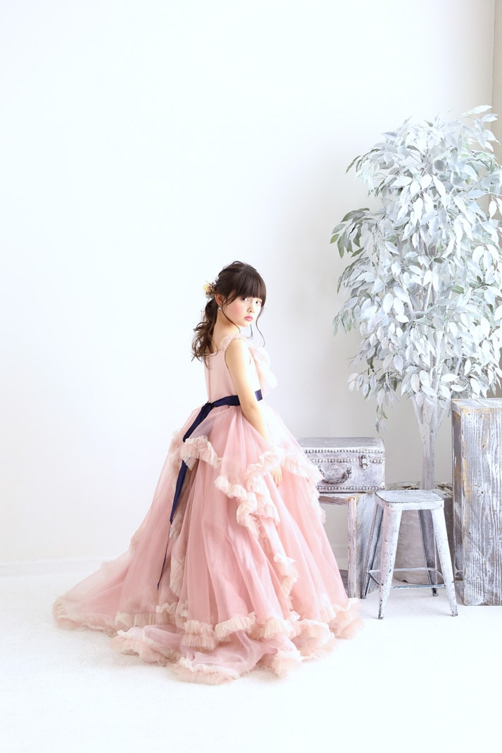 トレーンの長いピンクのドレスを着て振り返る七五三の女の子の写真