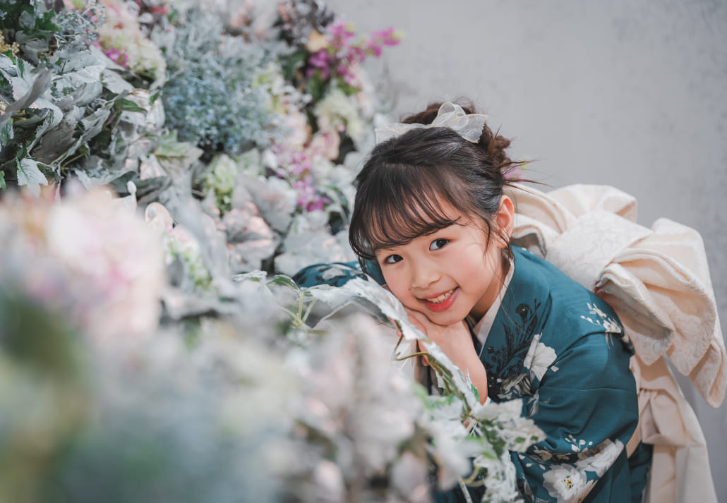 STUDIO ARCの七五三撮影ギャラリー、花の壁を背景に着物姿で微笑む女の子