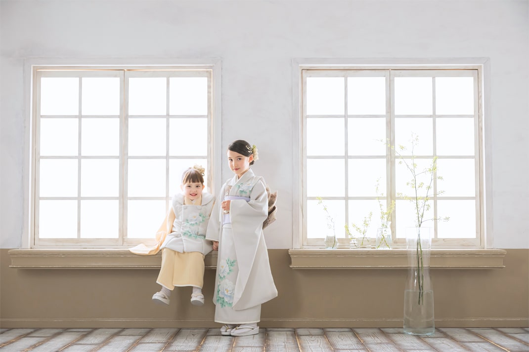 STUDIO ARCの七五三撮影ギャラリー、明るい窓辺で並ぶ着物姿の姉妹