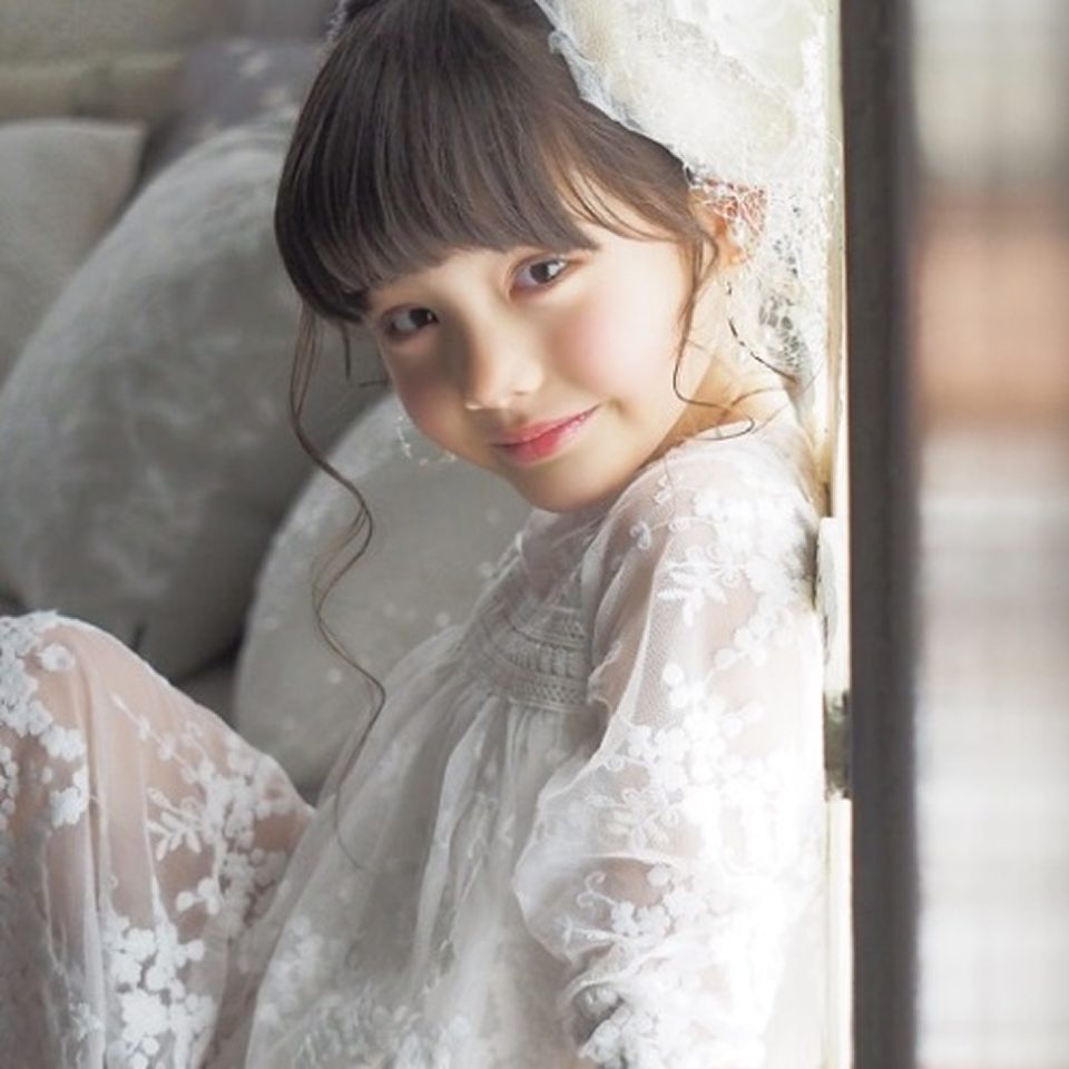 STUDIO ARCのキッズフォト。繊細な白いレースのドレスを着て、窓辺で優しく微笑む女の子のポートレート
