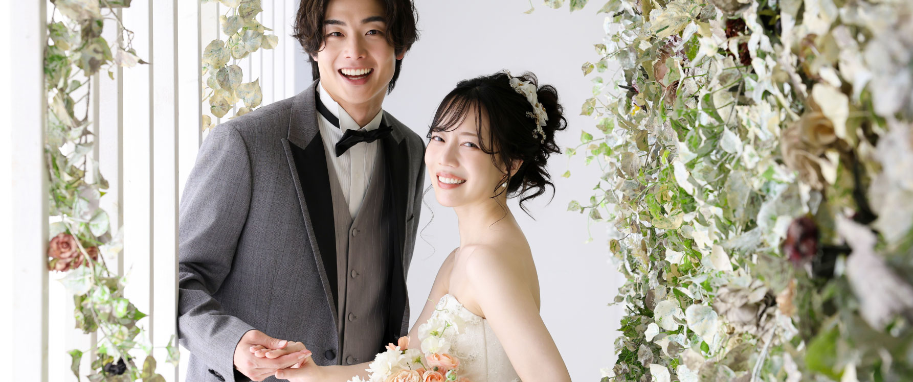 スタジオで撮影するウェディングドレスの新婦とタキシードの新郎