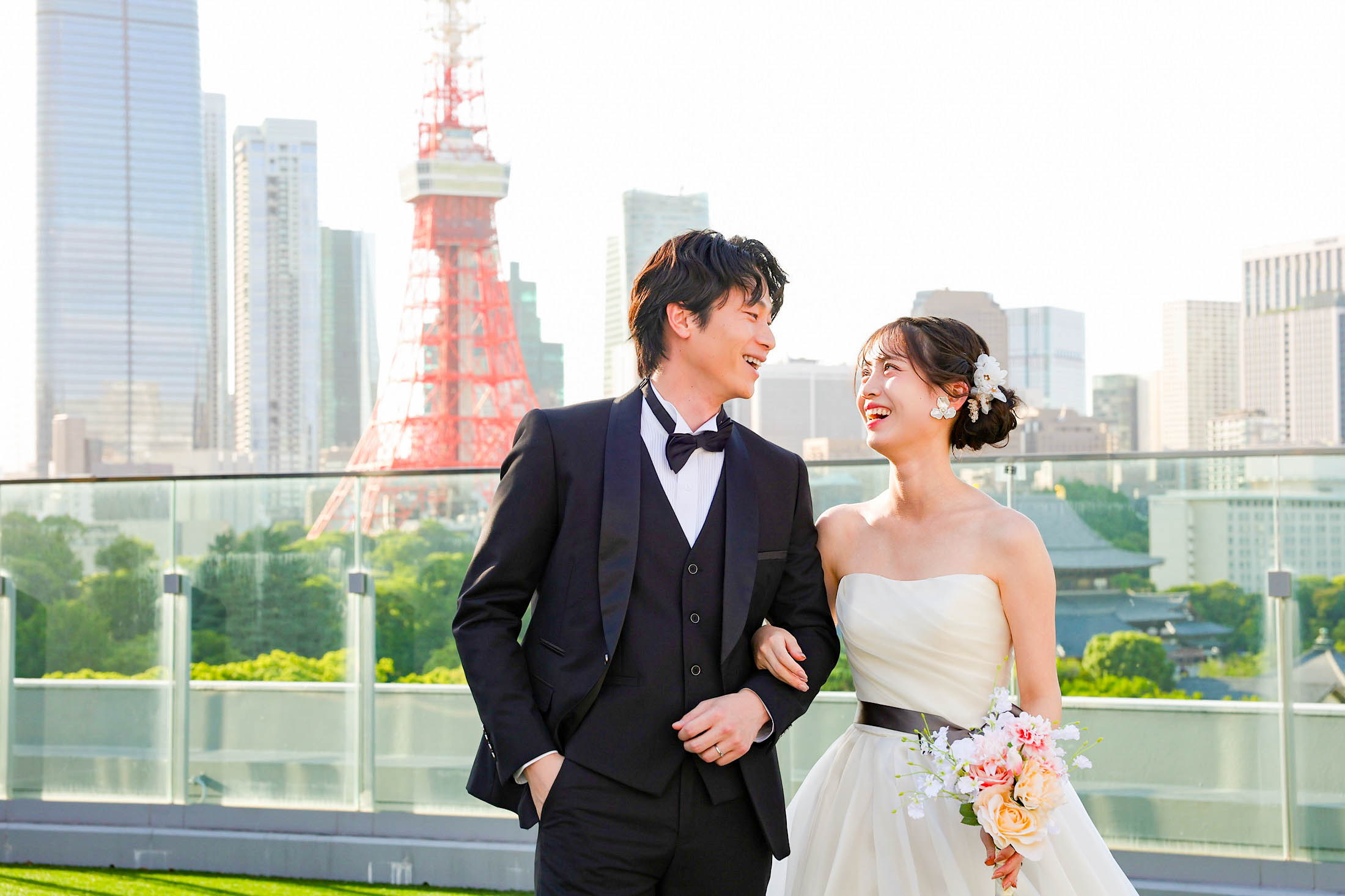 STUDIO ARC 芝Parkside STUDIO店の芝生のある屋上にて撮影。タキシードを着た新郎様とウェディングドレスを着てブーケを持った新婦様が東京タワーをバックに腕を組んで見つめ合っている写真。スタジオアーク芝 店舗住所:東京都港区芝2-1-28 芝アネックスビル1階