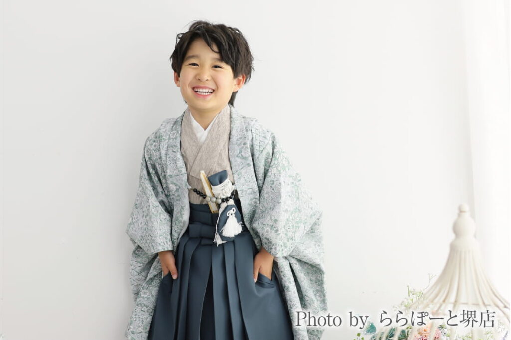 グリーンの着物とネイビーの袴で正面を向いて笑う七五三の男の子|ららぽーと堺店のスタジオ撮影