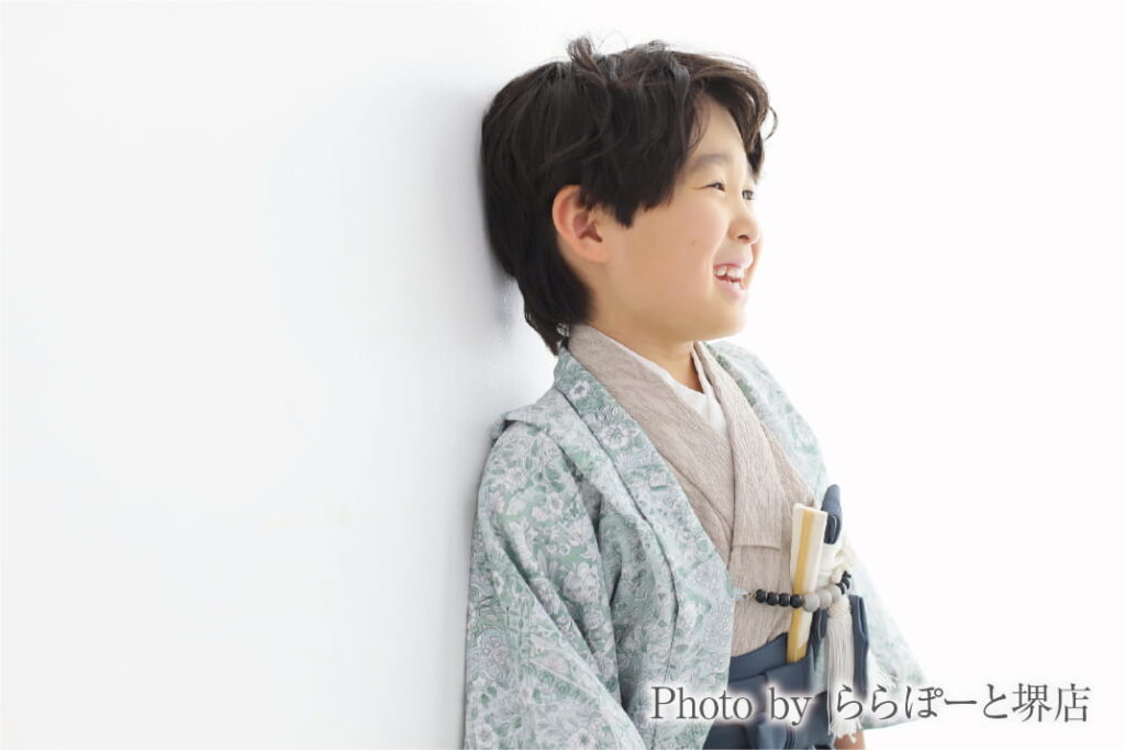 七五三の袴姿で白い壁にもたれて笑顔を見せる男の子|ららぽーと堺店のスタジオ撮影