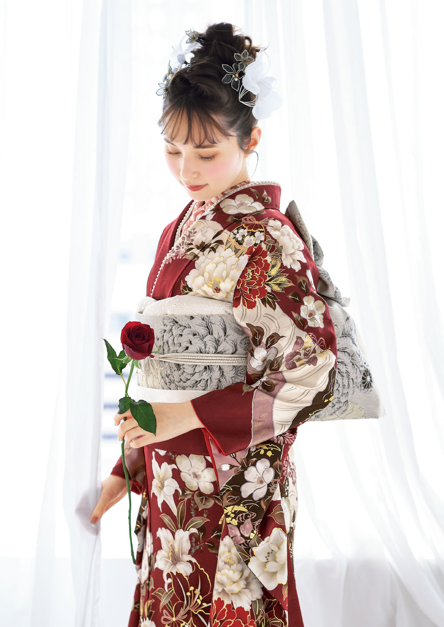 Coffret ワインレッドの地に紅白の牡丹や百合が描かれた振袖に白銀の菊柄袋帯を合わせたコーディネート