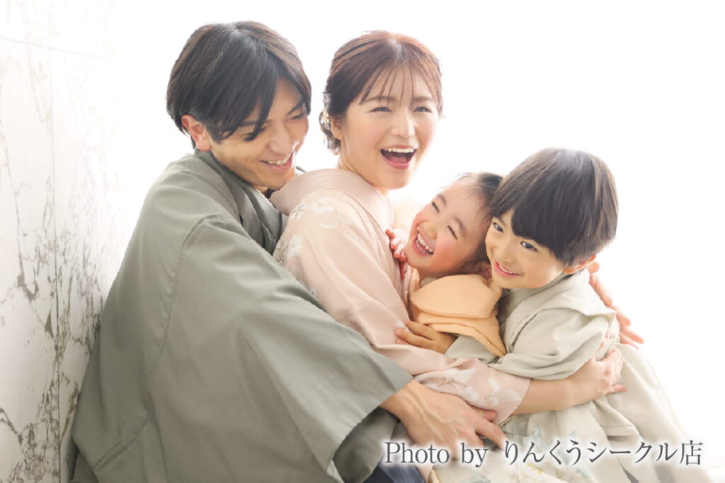 着物姿の家族4人が抱き合って笑顔を見せる家族写真｜りんくうシークル店で撮影