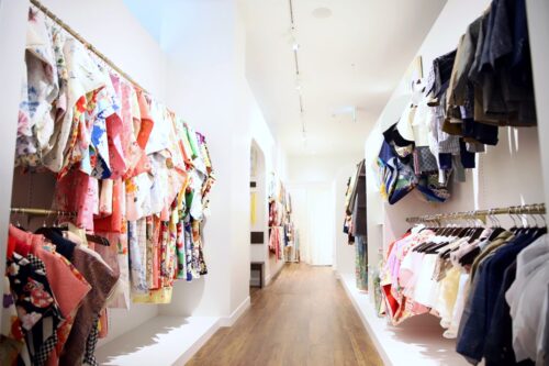 STUDIO ARCセブンパーク天美店の店内。両側の壁に色柄豊富な七五三の着物がずらりと並び、木目調の床の廊下が奥まで続いている。女の子用の花柄の着物、男の子用の羽織袴が種類豊富に揃った、明るく開放的な店内。