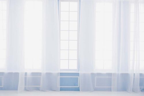 STUDIO ARCららテラスHARUMI FLAG店の店内装飾。水色の壁と大きな窓に並ぶ白いレースカーテン