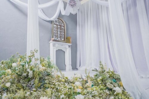 STUDIO ARCららテラスHARUMI FLAG店の店内装飾。白い暖炉風オブジェとグリーンや白の花々、紫のドレープカーテン