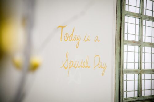 STUDIO ARC 錦糸町PARCO店の撮影セット。白い壁に黄色い手書き風の文字で「Today is a Special Day」と描かれ、右側にはアンティーク調のグリーンの格子窓がある、やさしく温かみのあるスタジオ空間。