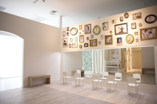 STUDIO ARCららぽーと門真店の店内。壁一面にアンティーク調のフレームで飾られた七五三の記念写真が並び、下には鏡と白い子供用の椅子が横一列に配置された着付け・ヘアメイクスペースが広がっている