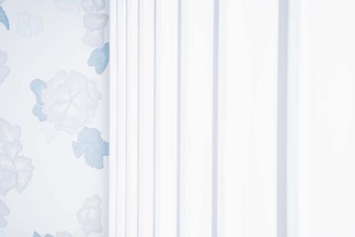 STUDIO ARCららぽーと立川立飛店の店内装飾。水色の花柄壁紙と白いプリーツカーテンが並ぶコーナー