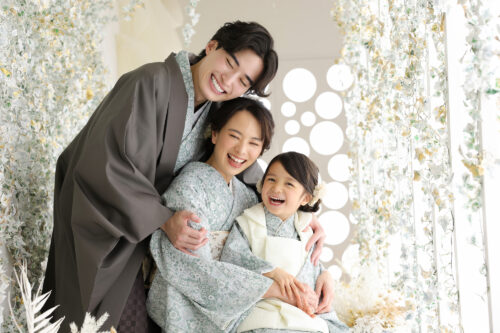 七五三3歳の家族写真。着物姿の両親と娘が寄り添い、家族全員が笑顔を見せている