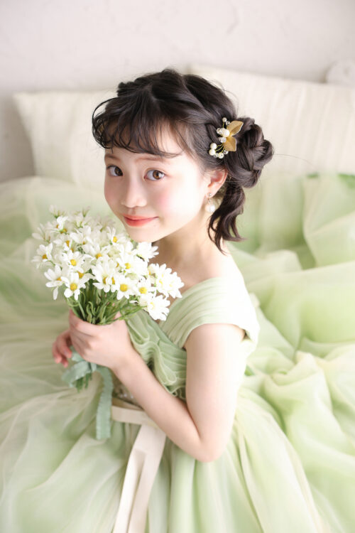 STUDIO ARCおおとり店で撮影した七五三7歳の女の子の記念写真。淡いグリーンのドレスを着て白い花束を手に、優しく微笑んでいる