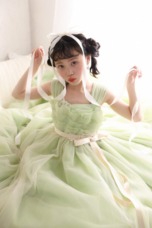 STUDIO ARCおおとり店で撮影した七五三7歳の女の子の記念写真。淡いグリーンのドレスを着て両手に白いリボンを持ち、少し澄ました表情を見せている