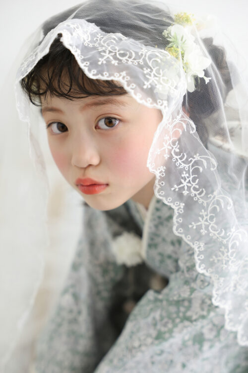 STUDIO ARCおおとり店で撮影した七五三7歳の女の子の記念写真。白いレースのベールを頭からかぶり、まっすぐカメラを見つめている