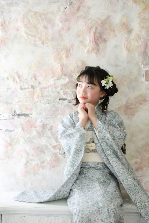 STUDIO ARCおおとり店で撮影した七五三の女の子の記念写真。淡いグリーンの着物姿で両手を組み、横を見上げている