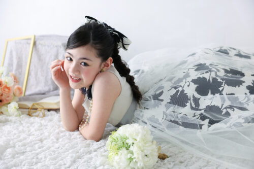 STUDIO ARC心斎橋店で撮影した七五三7歳の女の子の記念写真。白黒の花柄ドレスにパールのネックレスを合わせ、うつ伏せになって微笑んでいる