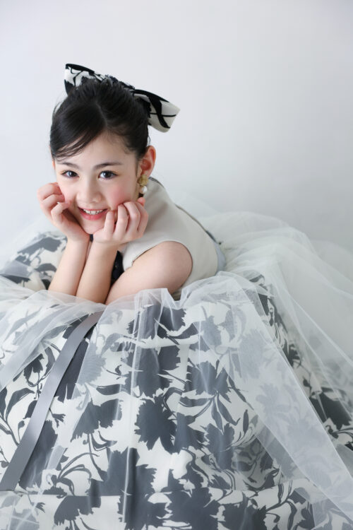 STUDIO ARC心斎橋店で撮影した七五三7歳の女の子の記念写真。白黒の花柄ドレスを着て頬に手を添え、満面の笑顔を見せている