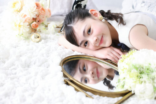 STUDIO ARC心斎橋店で撮影した七五三7歳の女の子の記念写真。アンティーク調の鏡に顔を映しながら、横になって微笑んでいる